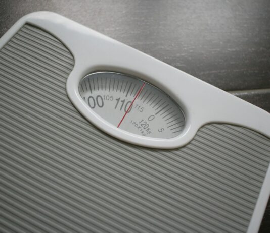 건강을 위한 동반자로서 다이어트와 운동 a bathroom scale sitting on top of a wooden table