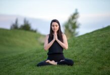 스트레스 관리를 위한 명상 woman in black tank top and black pants sitting on green grass field during daytime