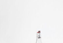 물, 충분히 마시고 있나요? rocks glass beside half empty bottle on white surface
