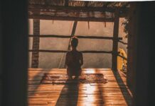 명상과 호흡법이 스트레스 해소에 미치는 영향 woman meditating on floor with overlooking view of trees