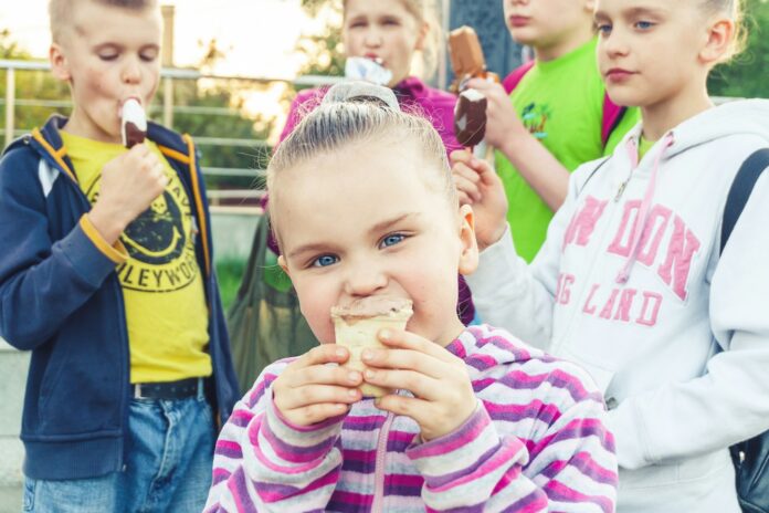 boy in white and pink striped long sleeve shirt holding ice cream