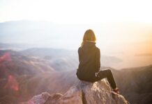 심리적 안정에 큰 역할을 하는 운동의 역할 person sitting on top of gray rock overlooking mountain during daytime