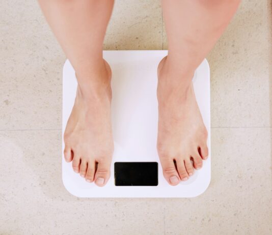 체중 감량과 호르몬의 관계: 내분비계가 다이어트에 미치는 영향 person standing on white digital bathroom scale