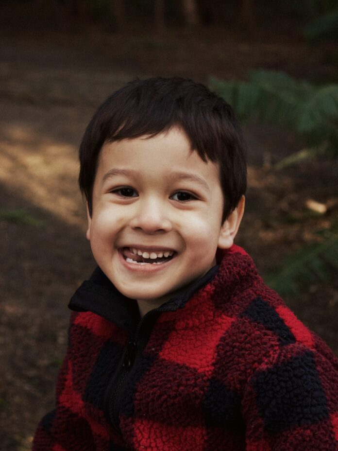 boy in red and black sweater smiling