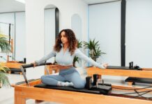 필라테스로 몸매 교정이 가능할까? a woman sitting on a piyor in a room